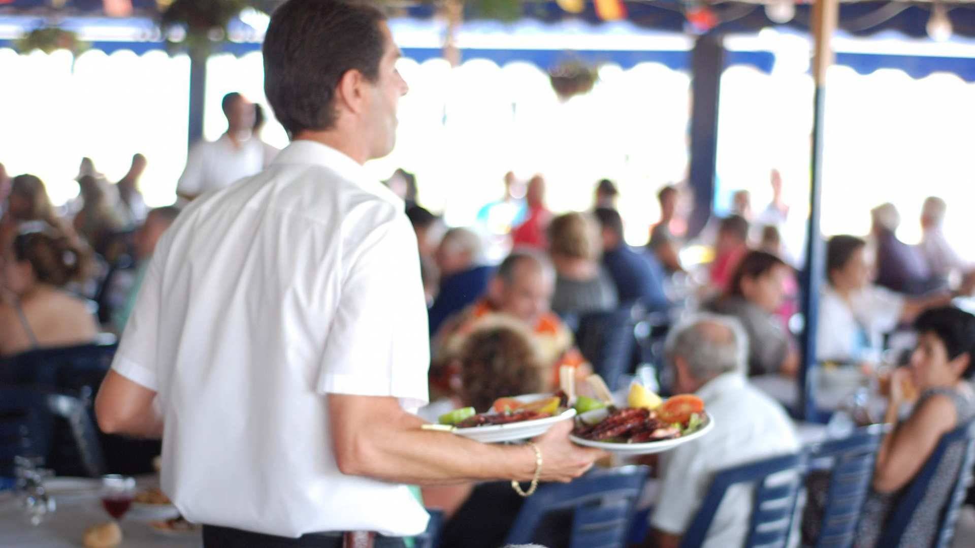 En el chiringuito El Tintero, los camareros avanzan entre las mesas subastando los platos.